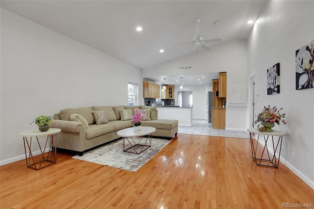 living room with light tile flooring, ceiling fan, and high vaulted ceiling