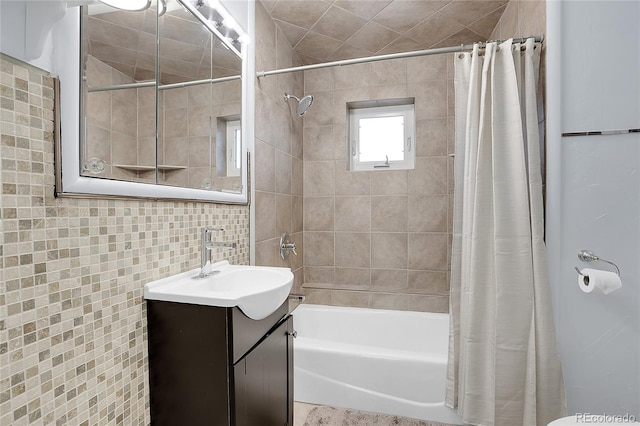 bathroom with tile walls, shower / tub combo with curtain, and vanity