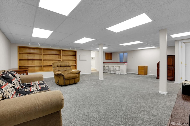 carpeted living room featuring a drop ceiling