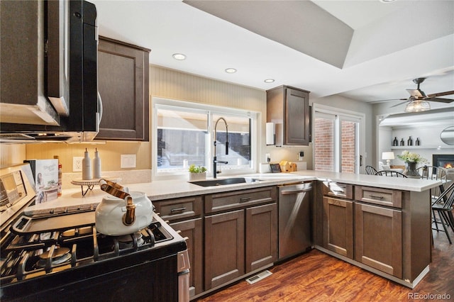 kitchen with ceiling fan, stainless steel dishwasher, kitchen peninsula, sink, and dark wood-type flooring