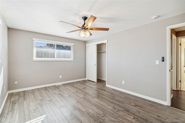 unfurnished bedroom with ceiling fan, a closet, and wood-type flooring