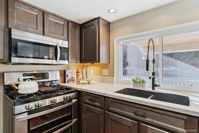 kitchen featuring appliances with stainless steel finishes, sink, and dark brown cabinets