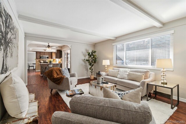 living room featuring dark wood-type flooring, beam ceiling, and ceiling fan