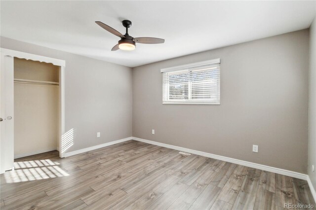 unfurnished bedroom with ceiling fan, a closet, and light wood-type flooring