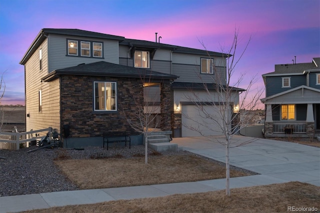 view of front of house featuring stone siding, concrete driveway, an attached garage, and fence