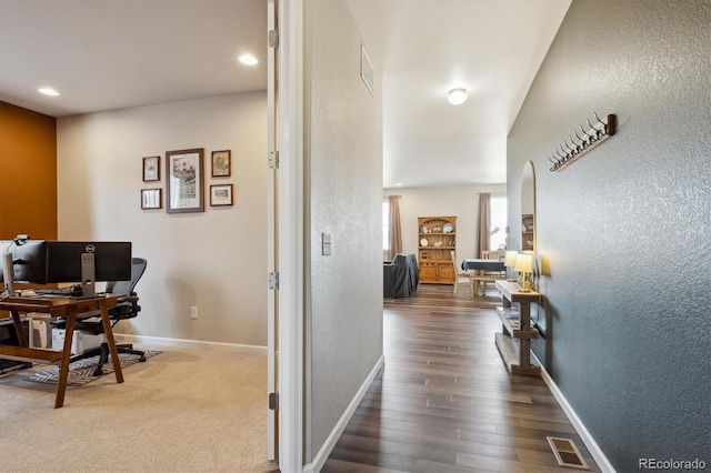 hall featuring visible vents and a textured wall