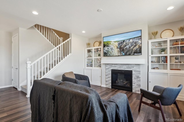 living area with stairs, recessed lighting, a stone fireplace, and wood finished floors