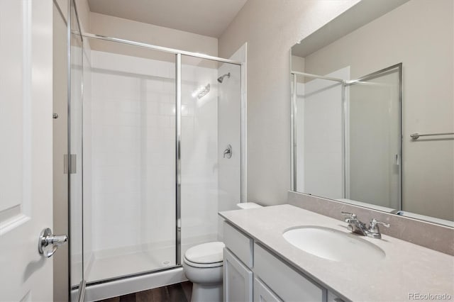 bathroom with toilet, a shower stall, and vanity