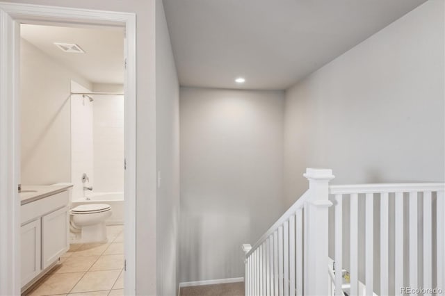 interior space with light tile patterned floors, visible vents, and an upstairs landing