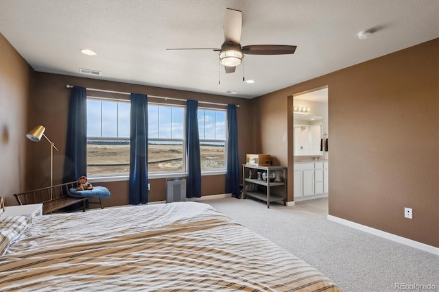 bedroom featuring visible vents, a ceiling fan, light carpet, ensuite bath, and baseboards