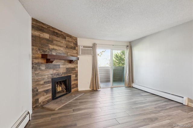 unfurnished living room featuring a baseboard radiator, a wall mounted air conditioner, a baseboard heating unit, a large fireplace, and wood finished floors