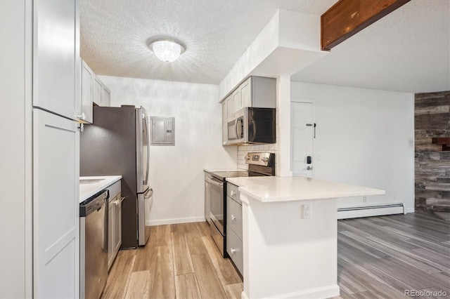 kitchen with stainless steel appliances, a baseboard radiator, a peninsula, light wood-style floors, and light countertops