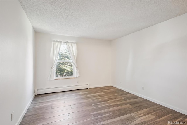 spare room featuring a baseboard radiator, wood finished floors, a textured ceiling, and baseboards