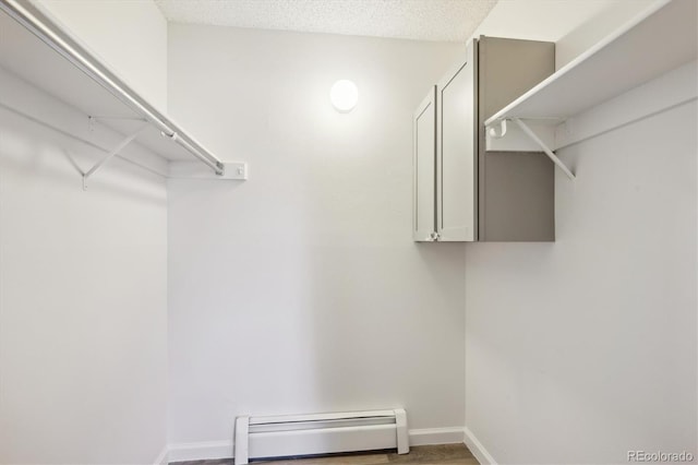 walk in closet with a baseboard heating unit and wood finished floors