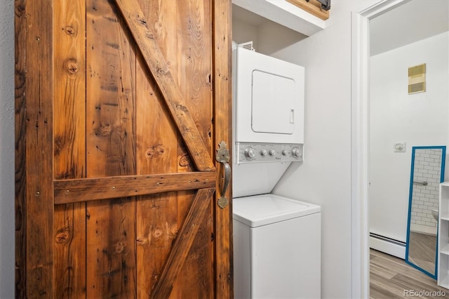 laundry room with stacked washer / dryer, a baseboard heating unit, and wood finished floors