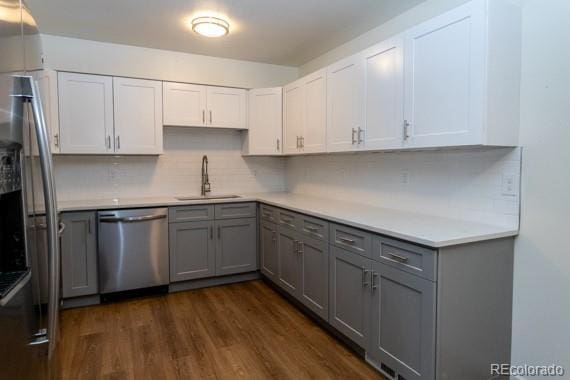 kitchen with white cabinets, dark hardwood / wood-style flooring, stainless steel appliances, sink, and gray cabinetry