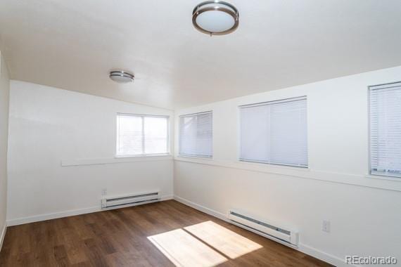 empty room with baseboard heating, lofted ceiling, and dark hardwood / wood-style flooring