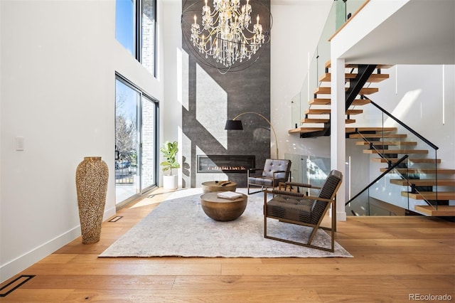 interior space featuring visible vents, stairway, wood finished floors, a high ceiling, and a fireplace