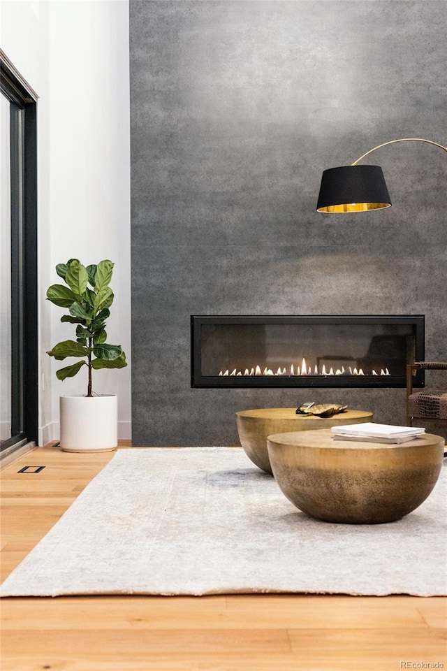 details with a lit fireplace, an accent wall, visible vents, and wood finished floors