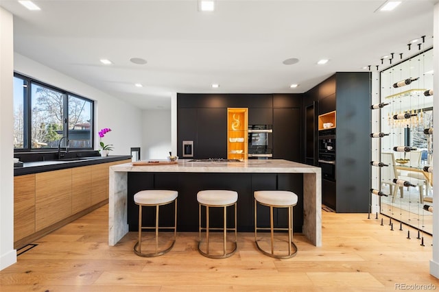 bar featuring recessed lighting, dobule oven black, a sink, light wood finished floors, and stainless steel gas stovetop