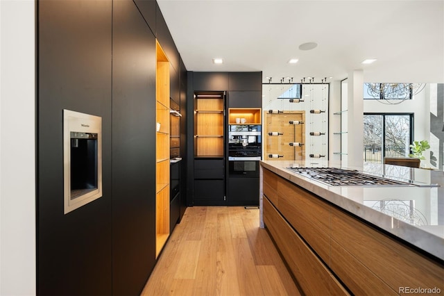 kitchen with brown cabinets, light wood-style floors, refrigerator with ice dispenser, modern cabinets, and dark cabinets