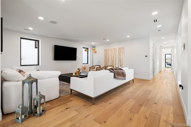 living area featuring a healthy amount of sunlight, light wood-style floors, baseboards, and recessed lighting