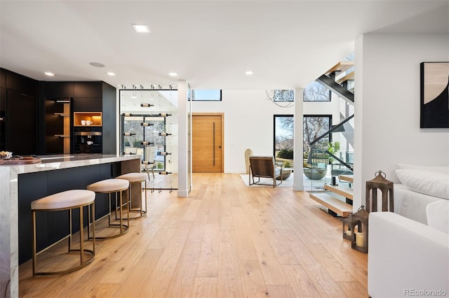 bar with stairs, light wood-style flooring, and recessed lighting