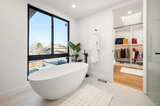 full bath with a freestanding bath, recessed lighting, tile patterned floors, and baseboards