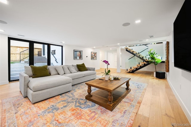 living area featuring recessed lighting, light wood-style flooring, baseboards, and stairs