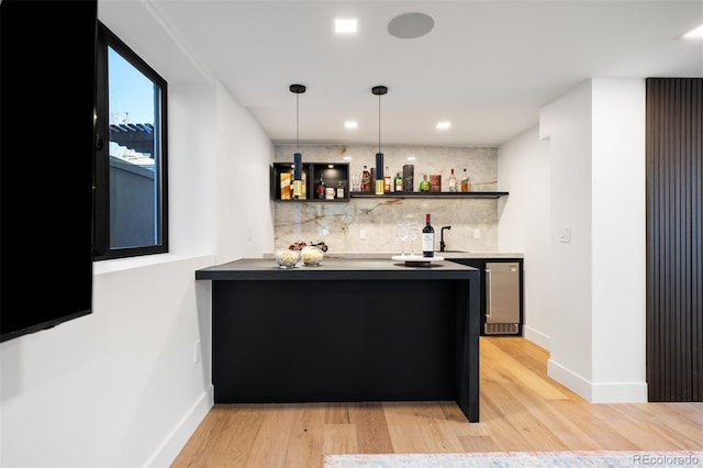 bar with tasteful backsplash, light wood-type flooring, indoor wet bar, and decorative light fixtures