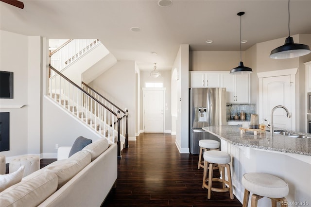 kitchen featuring light stone counters, backsplash, white cabinetry, appliances with stainless steel finishes, and sink