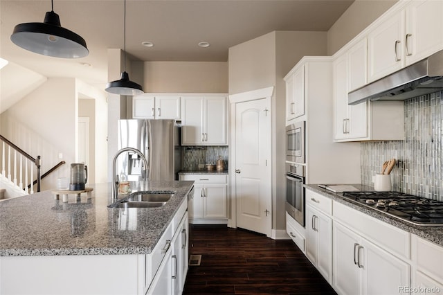 kitchen featuring pendant lighting, an island with sink, stainless steel appliances, white cabinetry, and sink