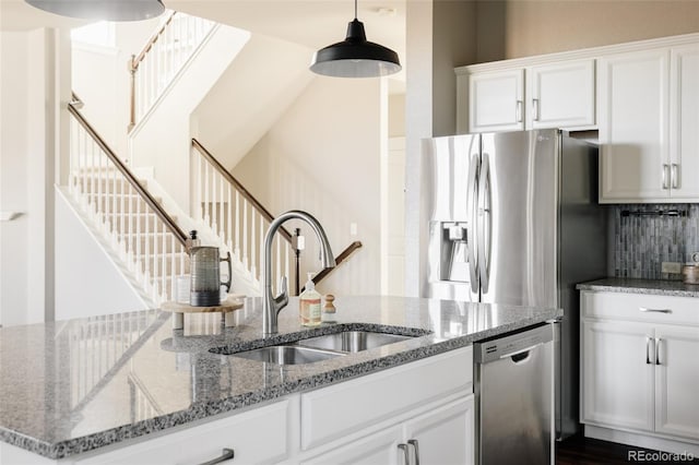 kitchen with light stone counters, appliances with stainless steel finishes, white cabinetry, and sink