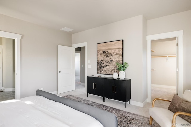 bedroom featuring light colored carpet, a closet, and a spacious closet