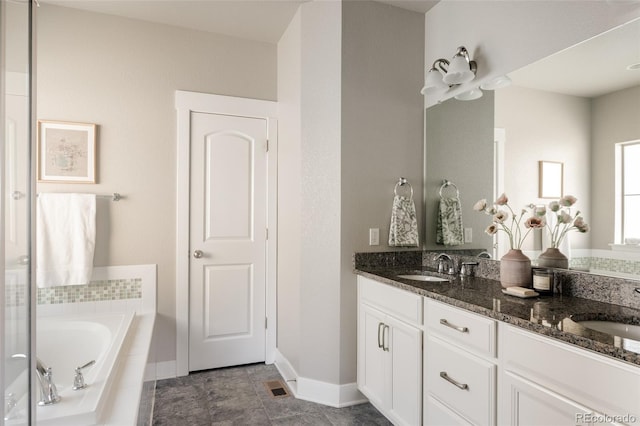 bathroom featuring tiled tub and vanity