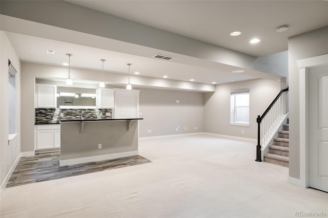 kitchen with a kitchen bar, white cabinetry, tasteful backsplash, and pendant lighting