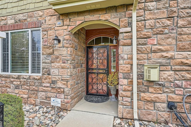 view of exterior entry with stone siding and brick siding