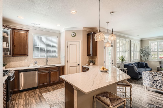 kitchen featuring dark wood-style flooring, a breakfast bar area, a textured ceiling, a sink, and stainless steel appliances