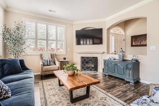living room featuring crown molding, arched walkways, baseboards, and dark wood-style floors