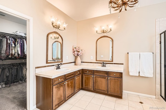 bathroom featuring double vanity, a sink, a walk in closet, and tile patterned flooring