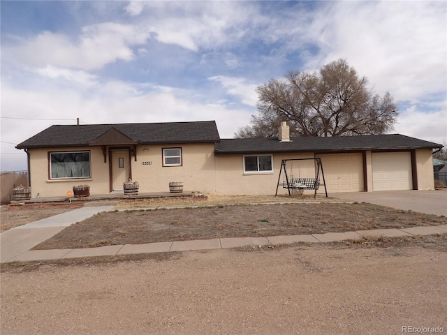 view of front of property with a shingled roof, concrete driveway, stucco siding, a chimney, and a garage