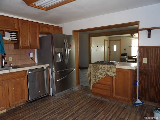 kitchen with tile countertops, a ceiling fan, dark wood-style floors, a sink, and stainless steel appliances