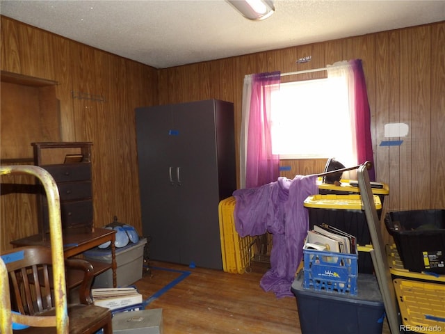 bedroom with wood finished floors, wood walls, and a textured ceiling