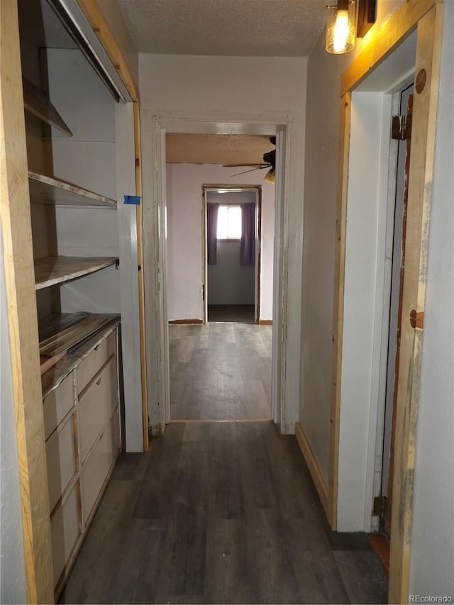 hall with baseboards, a textured ceiling, and dark wood finished floors