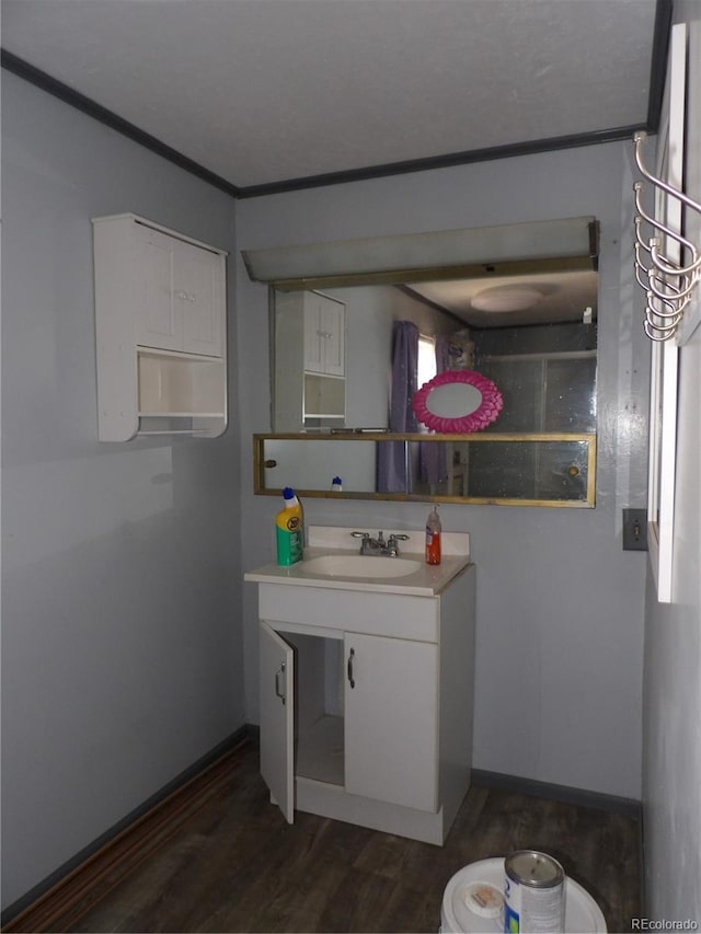 bathroom with baseboards, wood finished floors, vanity, and ornamental molding