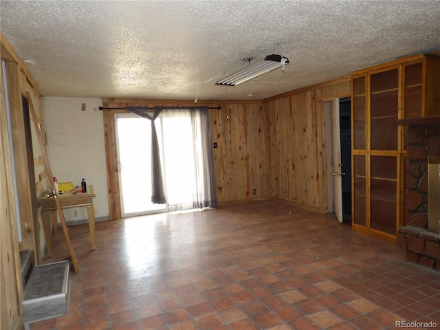 unfurnished room with wood walls and a textured ceiling