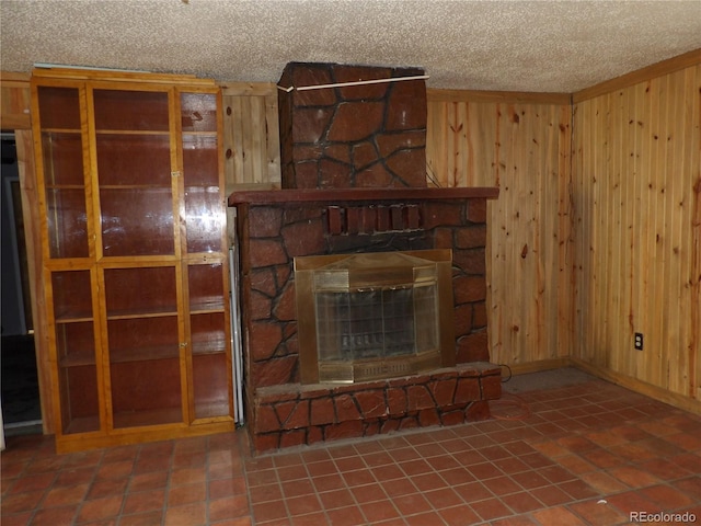 unfurnished living room with tile patterned floors, wooden walls, a fireplace, and a textured ceiling