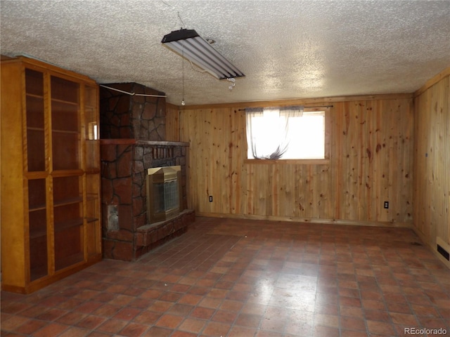 unfurnished living room with wooden walls, a fireplace, and a textured ceiling