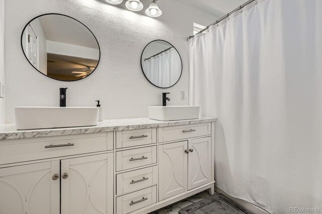 1179 S Fultondale Cir, Aurora, CO 80018 - full bathroom with double vanity, a shower with curtain, and marble look tiles