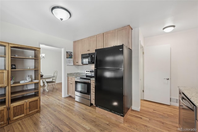 kitchen featuring light stone counters, light brown cabinetry, light wood-type flooring, and black appliances